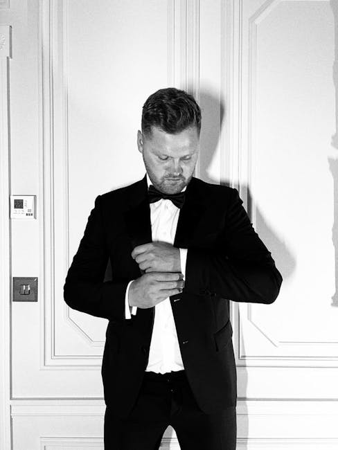 Stylish man in a tuxedo adjusting his cufflinks, exuding elegance in a London setting.